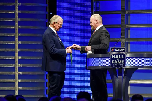 Coy Gibbs, right, presents the Hall of Fame ring to his father, NASCAR Hall of Fame inductee Joe Gibbs, during the induction ceremony in Charlotte, N.C., on Jan. 31, 2020. Coy, the vice chairman at Joe Gibbs Racing for his NFL and NASCAR Hall of Fame father, died Sunday morning, Nov. 6, 2022. He was 49. His death came just hour after his son Ty won the Xfinity Series championship. (AP Photo/Mike McCarn, File)