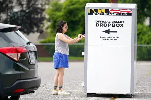 A woman drops a ballot into a drop box while casting her vote during Maryland's primary election, Tuesday, July 19, 2022, in Baltimore.  Whether a state requires voters to request an absentee ballot or participates in universal mail-in voting, all ballots cast by mail or dropped off at a drop box are vetted to ensure their legitimacy.(AP Photo/Julio Cortez, File)