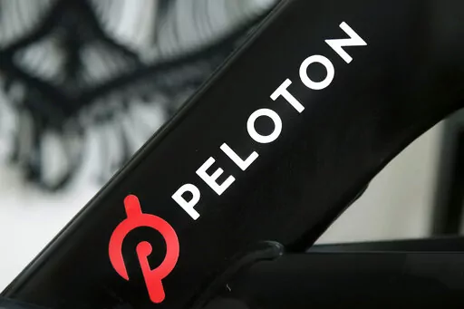 This Nov. 19, 2019 photo shows a Peloton logo on the company's stationary bicycle in San Francisco, Calif.  Peloton told employees Thursday, Oct. 6, 2022,  that it will cut approximately 500 jobs, or about 12% of its workforce, as post- pandemic sales of its indoor exercise equipment continues to tail off.  (AP Photo/Jeff Chiu, File)