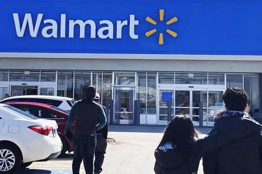 Shoppers walk to a Walmart in Vernon Hills, Ill., Tuesday, March 28, 2023. If you purchased some weighted groceries or bagged fruit at Walmart in recent years, you may be eligible for a cash payment from a class action settlement with the retailer. The class action lawsuit, which was first filed in October 2022, alleges that Walmart shoppers across the U.S. and Puerto Rico who purchased certain sold-by-weight meat and seafood as well as select citrus sold in bulk bags paid more than the lowest p