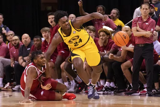 Arkansas' Kamani Johnson, left, pulls Missouri's Kobe Brown, right, to the court during the first half of an NCAA college basketball game Wednesday, Jan. 18, 2023, in Columbia, Mo. (AP Photo/L.G. Patterson)