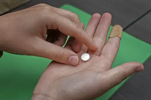 A patient prepares to take the first of two combination pills, mifepristone, for a medication abortion during a visit to a clinic in Kansas City, Kan., on, Oct. 12, 2022. (AP Photo/Charlie Riedel, File)