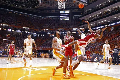 Arkansas guard Chris Lykes (11) falls to the floor as he shoots over Tennessee guard Josiah-Jordan James (30) during the second half of an NCAA college basketball game Saturday, March 5, 2022, in Knoxville, Tenn. (AP Photo/Wade Payne)