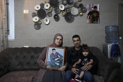 Maysoon, left, and Saleh Manasra, parents of Ahmad Manasra, who has been imprisoned by Israel since he was 13 when he was was convicted of attempted murder and sentenced to nine and a half years in prison, after his older cousin stabbed two Israelis, pose for a portrait with their daughter, Sham, in their home in east Jerusalem, Tuesday, Nov. 8, 2022. The 13 year-old Palestinian boy, whose case became a lighting rod for the Israeli-Palestinian conflict seven years ago, is now a man languishing i