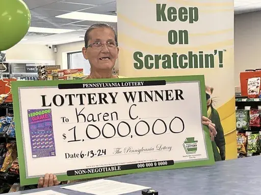 Freeport resident and $1 million Pennsylvania Lottery winner Karen Coffman celebrates her win holding a commemorative lottery check, Thursday, June 13, 2024, at the BP gas station in Freeport, Pa. Coffman’s husband expressed concern she might have financial difficulties after he died. Two weeks before he did in April, she netted $1 million with a scratch-off lottery ticket. (Joyce Hanz/Pittsburgh Tribune-Review via AP)