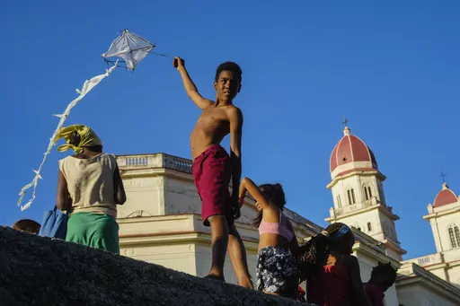 A youth flies a kite outside the shrine of the Virgin of Charity of Cobre in El Cobre, Cuba, on Saturday, Feb. 10, 2024. The Vatican-recognized Virgin, venerated by Catholics and followers of Afro-Cuban Santeria traditions, is at the heart of Cuban identity, uniting compatriots from the Communist-run Caribbean island to those who were exiled or emigrated to the U.S. (AP Photo/Ramon Espinosa)