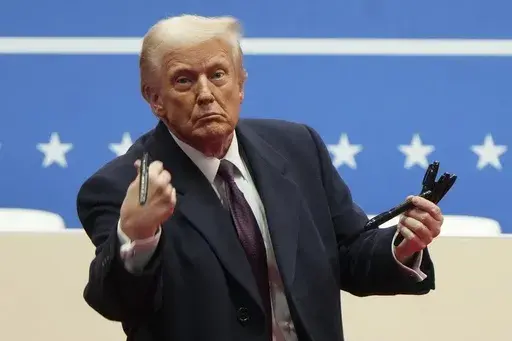 President Donald Trump throws pens used to sign executive orders to the crowd during an indoor Presidential Inauguration parade event in Washington, Jan. 20, 2025. (AP Photo/Matt Rourke, File)