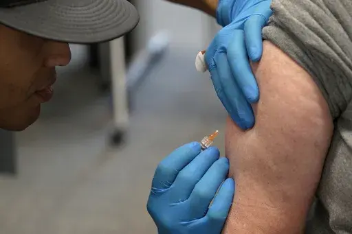 Matt Caldwell, left, a Lubbock Fire Department official, administers a measles, mumps and rubella vaccine to Clair May, 61, at the Lubbock Health Department, Feb. 26, 2025, in Lubbock, Texas. (AP Photo/Mary Conlon, File)