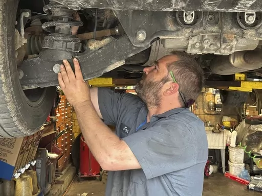 CORRECTS YEAR IN SECOND SENTENCE TO 2023 Mechanic Jon Guthrie inspects the underside of a 2014 Honda Ridgeline pickup truck at Japanese Auto Professional Service in Ann Arbor, Michigan. People are keeping their vehicles longer due to shortages of new ones and high prices. That drove the average U.S. vehicle age up to a record 12.5 years in 2023, according to S&P Global Mobility. (AP Photo/Tom Krisher)