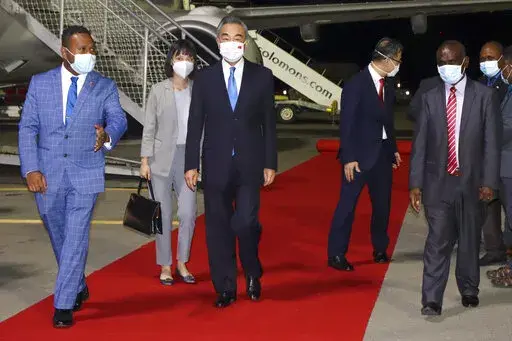 China's Foreign Minister Wang Yi, center, is escorted from his plane on his arrival in Honiara, Solomon Islands, early Thursday, May 26, 2022. Wang and a 20-strong delegation arrived in the Solomon Islands Thursday at the start of an eight-nation tour that comes amid growing concerns about Beijing’s military and financial ambitions in the South Pacific region. (AP Photo)