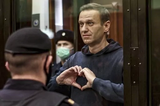 FILE In this file photo made from video provided by the Moscow City Court on Feb. 3, 2021, Russian opposition leader Alexei Navalny makes a heart gesture standing in a cage during a hearing to a motion from the Russian prison service to convert the suspended sentence of Navalny from the 2014 criminal conviction into a real prison term in the Moscow City Court in Moscow, Russia. Navalny, President Vladimir Putin's fiercest foe, has become Russia's most famous political prisoner. He is serving a n
