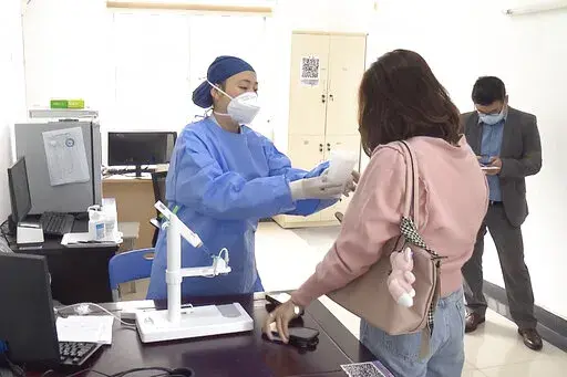 In this photo taken from video released by Shanghai Media Group, a medical worker hands over aerosolised COVID vaccine developed by Chinese biopharmaceutical company CanSino Biologics Inc. in Shanghai on Wednesday, Oct. 26, 2022. The Chinese city of Shanghai started administering the inhalable COVID-19 vaccine on Wednesday in what appears to be a world first. (Shanghai Media Group via AP)