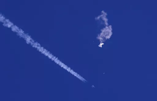 A fighter jet flies past the remnants of a large balloon after it was shot down above the Atlantic Ocean, just off the coast of South Carolina near Myrtle Beach, Feb. 4, 2023. The Defense Department and the Federal Aviation Administration have been tracking a balloon that was flying off the coast of Hawaii last week. A defense official says there’s no indication it is connected to China or any other adversary, and it presents no threats to aviation or national security. (Chad Fish via AP, File