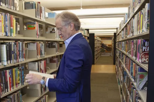 Nate Coulter, executive director of the Central Arkansas Library System (CALS), looks at a book in the main branch of the public library in downtown Little Rock, Ark., on May 23, 2023. Arkansas is temporarily blocked from enforcing a law that would have allowed criminal charges against librarians and booksellers for providing “harmful” materials to minors, a federal judge ruled Saturday, July 29. (AP Photo/Katie Adkins, File)