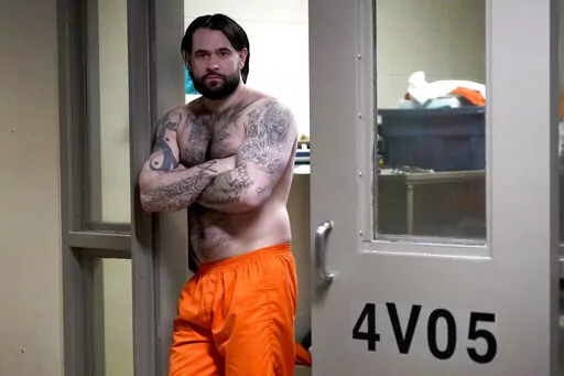 Erik Eck, a former member of the Latin Kings gang stands in the doorway of his cell at the DuPage County, Ill., Jail displaying tattoos that symbolize his status with the gang, Thursday, Feb. 3, 2022, in Wheaton, Ill. Under penalty of a beating or death, Eck pledged when he joined the Latin Kings in Chicago at 13 to adhere to the gang's first rule: "Once a King, always a King." Tattoos that cover his entire body express fealty forever to the gang, one of the nation's largest. (AP Photo/Charles R