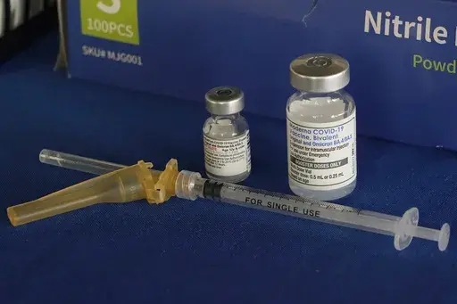 A syringe lies next to vials of COVID-19 booster vaccines at an inoculation station in Jackson, Miss., Friday, Nov. 18, 2022. (AP Photo/Rogelio V. Solis, File)