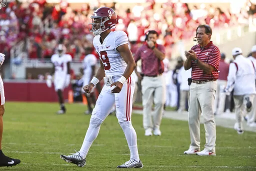 Alabama quarterback Bryce Young and coach Nick Saban celebrate a touchdown against Arkansas during the second half of an NCAA college football game Saturday, Oct. 1, 2022, in Fayetteville, Ark. Young left the game in the first half after an injury. (AP Photo/Michael Woods)