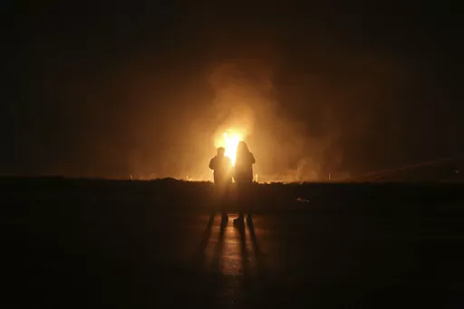 Two men look at flames after a natural gas pipeline explodes outside the city of Boroujen in the western Chaharmahal and Bakhtiari province, Iran, in early Wednesday, Feb. 14, 2024. Explosions struck a natural gas pipeline in Iran early Wednesday, with an official blaming the blasts on a "sabotage and terrorist action" in the country as tensions remain high in the Middle East amid Israel's war on Hamas in the Gaza Strip. (Reza Kamali Dehkordi/Fars News Agency via AP)