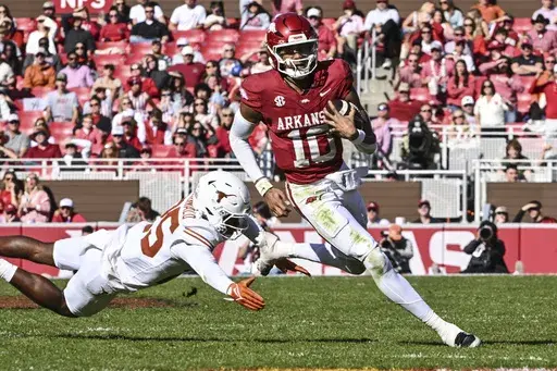 Arkansas quarterback Taylen Green (10) slips past Texas defensive back Jelani McDonald (25) as he runs the ball during the second half of an NCAA college football game Saturday, Nov. 16, 2024, in Fayetteville, Ark. (AP Photo/Michael Woods)