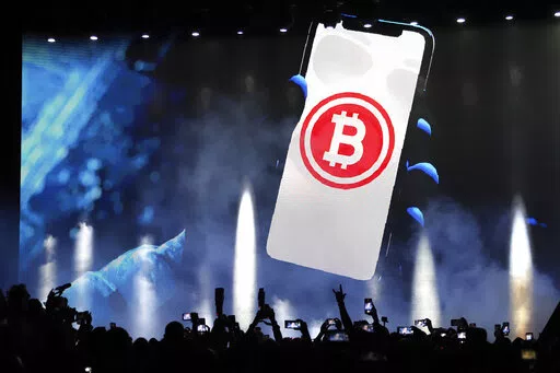 A bitcoin symbol is presented on an LED screen during the closing ceremony of a congress for cryptocurrency investors in Santa Maria Mizata, El Salvador, Saturday, Nov. 20, 2021. The Central American country´s Finance Minister Alejandro Zelaya said Wednesday, June 15, 2022, that El Salvador has not suffered financial losses from its controversial investment in bitcoin. (AP Photo/Salvador Melendez, File)