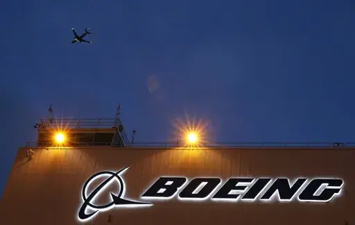 An airplane flies over a sign on Boeing's newly expanded 737 delivery center, Oct. 19, 2015, at Boeing Field in Seattle. The U.S. Justice Department plans to propose that Boeing plead guilty to fraud in connection with two deadly plane crashes involving its 737 Max jetliners, according to two people who heard federal prosecutors detail the offer Sunday, June 30, 2024. (AP Photo/Ted S. Warren, File)