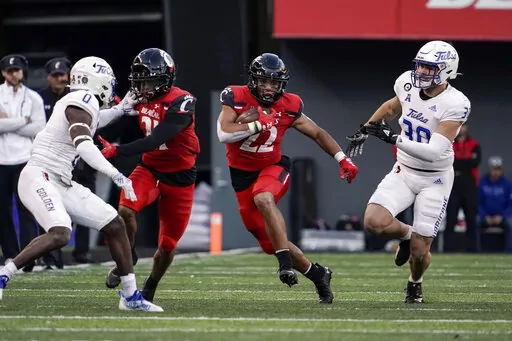 Cincinnati running back Ryan Montgomery (22) runs with the ball during the second half of an NCAA college football game against Tulsa Saturday, Nov. 6, 2021, in Cincinnati. Another competition playing out in camp is to replace 1,300-yard running back Jerome Ford. The returning candidates are senior Ryan Montgomery, who's been a top-notch punt returner for the Bearcats for three years, and senior Charles McClelland, who has had some bad luck with injuries. (AP Photo/Jeff Dean, File)