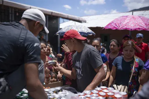 Locals in Guatemala offer sodas to Mexicans who fled their town of Amatenango, Mexico and crossed the border to Ampliación Nueva Reforma, Guatemala, to escape cartel violence in Mexico, Thursday, July 25, 2024. Some refugees are staying at the school and others at locals' homes. (AP Photo/Santiago Billy)
