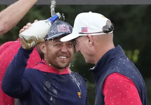 United States team member Xander Schauffele pours champagne on captain Jim Furyk as the team celebrates after winning the Presidents Cup golf tournament at Royal Montreal Golf Club, Sunday, Sept. 29, 2024, in Montreal. (Frank Gunn/The Canadian Press via AP)
