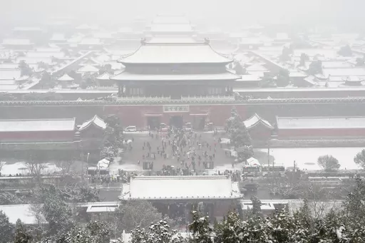 The snow covered Forbidden City is seen from a hilltop pavilion in Beijing, Wednesday, Dec. 13, 2023. Throngs of people in boots and down parkas climbed a hill that overlooks the Forbidden City this week to jostle with others trying to get a shot of the snow-covered roofs of the former imperial palace. (AP Photo/Ng Han Guan)