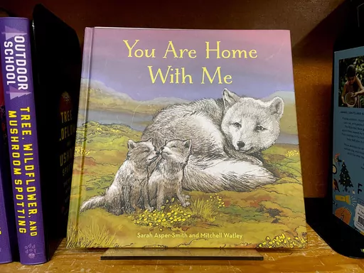The children's book "You Are Home With Me," illustrated by Mitchell Thomas Watley, is shown at a bookstore in Portland, Ore. in this April 5, 2023 photo. Publisher Sasquatch books, owned by Penguin Random House, said Wednesday, April 5, 2023, it has ended its publishing relationship with Watley after he was arrested on allegations of leaving violent, transphobic notes in stores around Juneau, Alaska. Watley told police he was motivated by fear following a deadly school shooting in Nashville that