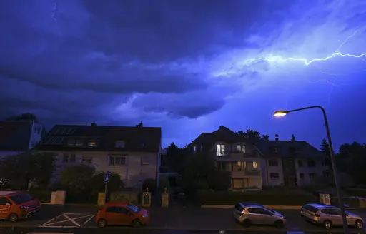 In this shot with slow shutter speed, lightning discharges in the evening sky during a heavy thunderstorm over the houses in the district of Sachsenhausen, Frankfurt/Main, Germany Wednesday, Aug. 16, 2023. Heavy rain in parts of Germany caused flooding and led to dozens of flight cancelations at Frankfurt Airport, the country's busiest and a major European hub, authorities said Thursday. (Arne Dedert/dpa via AP)