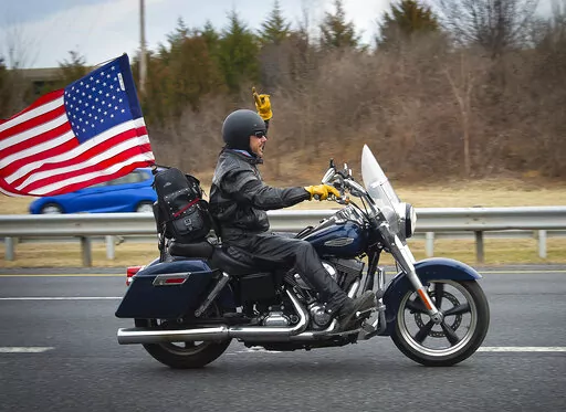 A supporter rides a motorcycle near the New Design Road bridge over I-270 in Frederick County as the “People’s Convoy” passed through the county as they made their way from Hagerstown to Washington, Sunday, March 6, 2022. (Bill Green/The Frederick News-Post via AP)