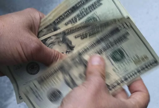 FILE- In this June 15, 2018, file photo, twenty dollar bills are counted in North Andover, Mass. Kids absorb money lessons whether you intend for them to do so or not. They observe your spending decisions, overhear your money talks, get spoiled by grandparents, and wonder why friends have different-looking lives. Your actions and conversations can model positive financial behaviors for all the kids in your life, whether they’re toddlers or teenagers. (AP Photo/Elise Amendola, File)