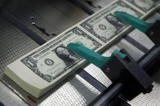 FILE- In this Nov. 15, 2017, file photo, new $1 bills with the signatures of U.S. Treasurer Jovita Carranza and Treasury Secretary Steven Mnuchin are cut and stacked at the Bureau of Engraving and Printing in Washington.  Want to quit your job? You’re not just walking away from a paycheck. If you’re not thoughtful with your exit strategy, you may leave money behind in less obvious places, like your commuter account or health savings plan.   (AP Photo/Jacquelyn Martin, File)