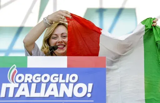 FILE — Giorgia Meloni holds an Italian flag as she addresses a rally in Rome, Saturday, Oct. 19, 2019. With God, homeland and "natural" family prominent in her political manifesto, Giorgia Meloni, whose Fratelli d'Italia (Brothers of Italy) party with neo-fascist roots has been fast rising in popularity in view of the upcoming Sept. 25 elections for Parliament, is positioning herself to become Italy's first far-right premier and the first woman to hold that office. (AP Photo/Andrew Medichini)