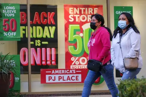 Black Friday shoppers wearing face masks shop at the Citadel Outlets in Commerce, Calif., Nov. 26, 2021. The holiday season is full of sneaky costs, expensive travel and the pressure to spend. It’s a time that leaves many Americans in debt long after the decorations come down. But with some planning and the patience to hunt for deals, you can still enjoy a meaningful season without spending hundreds of dollars in interest payments. (AP Photo/Ringo H.W. Chiu, File)