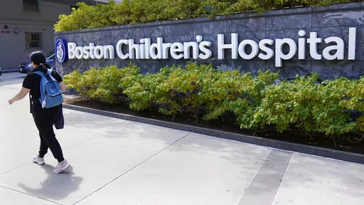 FILE — A woman walks past a sign outside the Boston Children's Hospital, Thursday, Aug. 18, 2022, in Boston. The American Academy of Pediatrics, the American Medical Association and the Children's Hospital Association are asking U.S. Attorney General Merrick Garland to investigate and prosecute people who are threatening violence against children's hospitals and physicians that provide gender-affirming health care. (AP Photo/Charles Krupa, File)