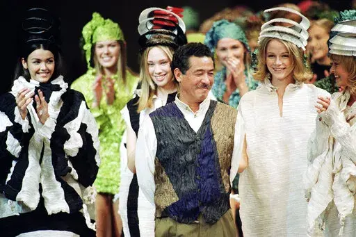 Japanese fashion designer Issey Miyake smiles standing among models after the presentation of his "1993/1994 fall/winter ready to wear collection" on March 17, 1993 in Paris, France. Miyake, who built one of Japan’s biggest fashion brands and was known for his boldly sculpted pleated pieces as well as former Apple CEO Steve Jobs’ black turtlenecks, has died. He was 84. He died Aug. 5, 2022, of liver cancer, Miyake Design Office said Tuesday, Aug. 9. (AP Photo/Lionel Cirroneau, File)