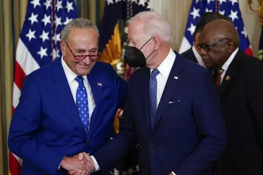 President Joe Biden shakes hands with Senate Majority Leader Chuck Schumer of N.Y., after signing the Democrats' landmark climate change and health care bill in the State Dining Room of the White House in Washington, Tuesday, Aug. 16, 2022. At back right is Rep. James Clyburn, D-S.C. (AP Photo/Susan Walsh)