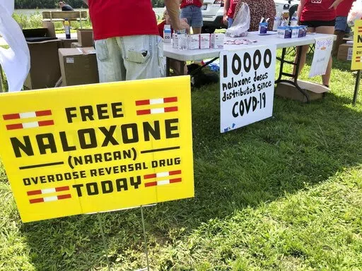 Signs are displayed at a tent during a health event on June 26, 2021, in Charleston, W.Va. The effort to hold drug companies, pharmacies and distributors accountable for their role in the opioid crisis has led to a whirlwind of legal activity around the United States. New legal settlements are being reached practically every week to provide governments money to fight the crisis, and in some cases funds for medicines to reverse overdoses or to help with treatment. (AP Photo/John Raby, File)