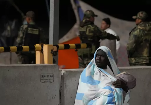 A migrant holds a child as he waits unable to cross the border from Chile into Peru, Thursday, April 27, 2023. A migration crisis at the border between Chile and Peru is intensifying, with hundreds of people stranded, unable to cross into Peru in an effort to return to their homes, as the mostly Venezuelan migrants seek to continue on to their home country but Peru isn't allowing them to enter because they lack documents. (AP Photo/Martin Mejia)