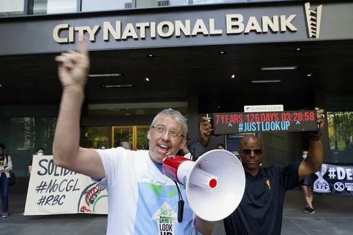 Adam McKay, left, director of the film "Don't Look Up," joins members of the Youth Climate Los Angeles coalition and others protesting climate change outside City National Bank in Los Angeles, Friday, March 18, 2022. On Tuesday Sept. 20, 2022, McKay announced a $4 million donation to the Climate Emergency Fund, an organization dedicated to getting money into the hands of activists engaged in disruptive, nonviolent demonstrations urging swifter action on climate change. (AP Photo/Damian Dovargane