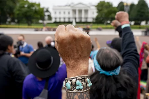 Wolf Ramerez of Houston, Texas, center, joins others with the Carrizo Comecrudo Tribe of Texas in holding up his fists as indigenous and environmental activists protest in front of the White House in Washington, Oct. 11, 2021. Members of the Native American Journalists Association are voting on whether to change the name to the Indigenous Journalists Association. (AP Photo/Andrew Harnik, file)