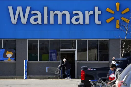 A woman pushes a shopping cart at a Walmart in Rolling Meadows, Ill. The company said in a memo Tuesday, Jan. 24, 2023, that U.S. workers will get pay raises next month, increasing starting wages to between $14 and $19 an hour. (AP Photo/Nam Y. Huh, File)