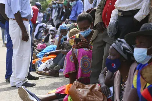 A woman reads messages on her mobile phone while waiting in a bank queue in Harare, Zimbabwe on Monday, Dec. 13, 2021. In Zimbabwe and other African nations, the virus's resurgence is threatening the very survival of millions of people who have already been driven to the edge by a pandemic that has devastated their economies. When putting food on the table is not a given, worries about whether to gather with family members for the holiday or heed public announcements urging COVID-19 precautions 