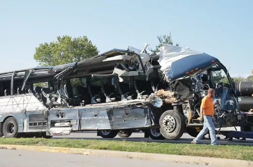 A worker helps clear the wreckage of a Greyhound bus that collided with tractor-trailers on the exit ramp to a rest area on westbound Interstate 70 in Highland, Ill., on Wednesday, July 12, 2023. (Christian Gooden/St. Louis Post-Dispatch via AP)