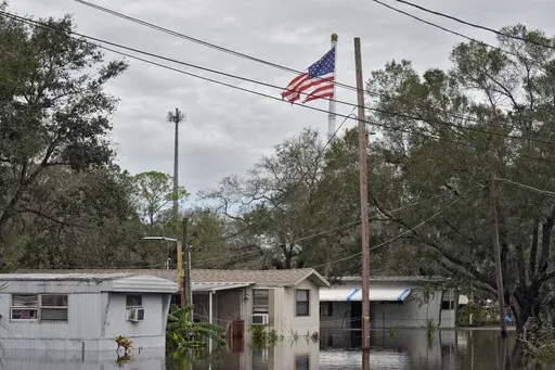 A tattered American flag flies above flooded homes, from Hurricane Milton along the Alafia river Friday, Oct. 11, 2024, in Lithia, Fla. (AP Photo/Chris O'Meara)