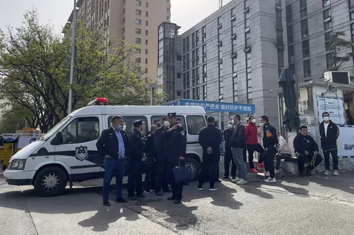 Police officers and security guards gather outside the barricaded hospital following a fire at a hospital in Beijing, Wednesday, April 19, 2023. More than a dozen people have died in a fire at a Beijing hospital that forced the evacuation of dozens of patients on Tuesday, Chinese state media reported. (AP Photo/Andy Wong)
