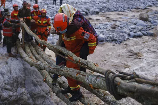In this photo released by Xinhua News Agency, rescuers carry a villager across a river following an earthquake in Moxi Town of Luding County, southwest China's Sichuan Province on Monday, Sept. 5, 2022. Dozens people were reported killed and missing in a 6.8 magnitude earthquake that shook China's southwestern province of Sichuan on Monday, triggering landslides and shaking buildings in the provincial capital of Chengdu, whose 21 million residents are already under a COVID-19 lockdown. (Cheng Xu