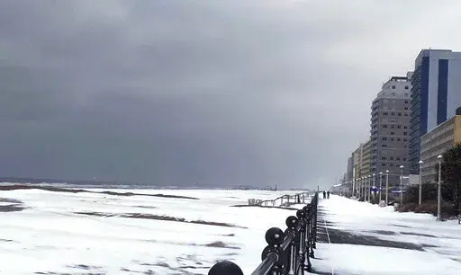 Snow covers the Virginia Beach oceanfront, Saturday, Jan. 22, 2022 in Virginia Beach, Va.  A layer of ice and a blanket of snow has covered coastal areas stretching from South Carolina to Virginia. The winter weather system that entered the region on Friday brought colder temperatures and precipitation not often seen in the region. (Stacy Parker/The Virginian-Pilot via AP)